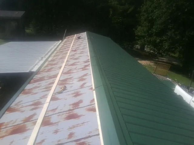 Old rusted panels beside newly installed green metal roofing — Wind Damage Roof Repair by Roofing Brothers in Bay Shore