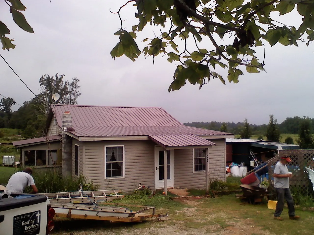 Crew finishing a mauve metal roof on a small farmhouse in Bay Shore
