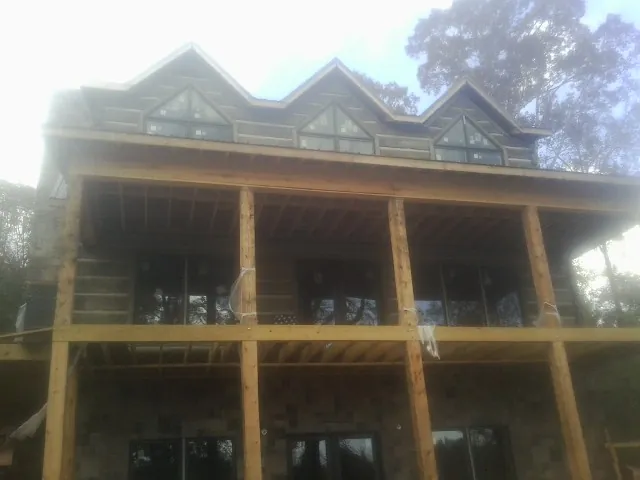 Dormers and porch framing on a large log home under construction — Roof Coating work by our crew in Bay Shore