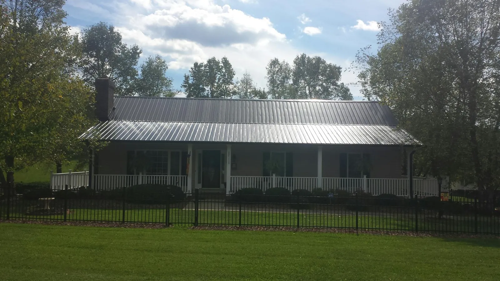 Gray metal roof on a brick ranch with a full width front porch — Gutter Guard Installation work by our crew in Bay Shore