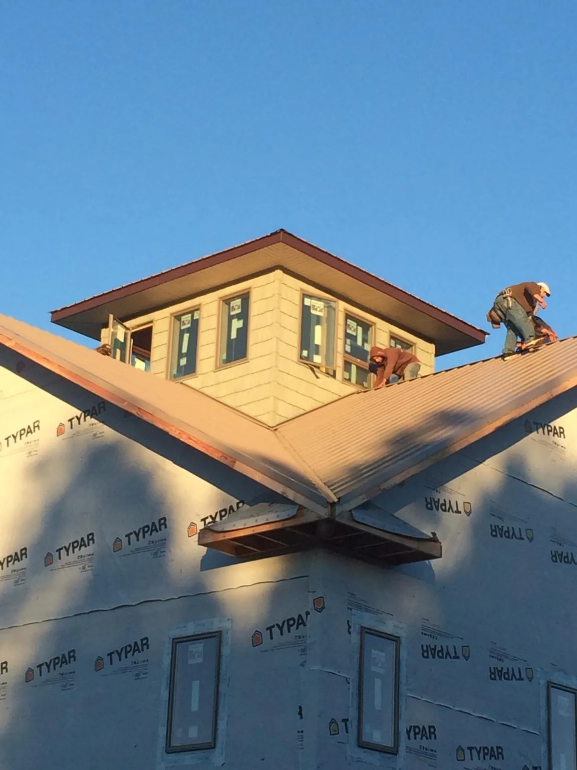 Roofers working around a rooftop cupola on a new metal roof at sunset — Roof Waterproofing in Bay Shore by Roofing Brothers